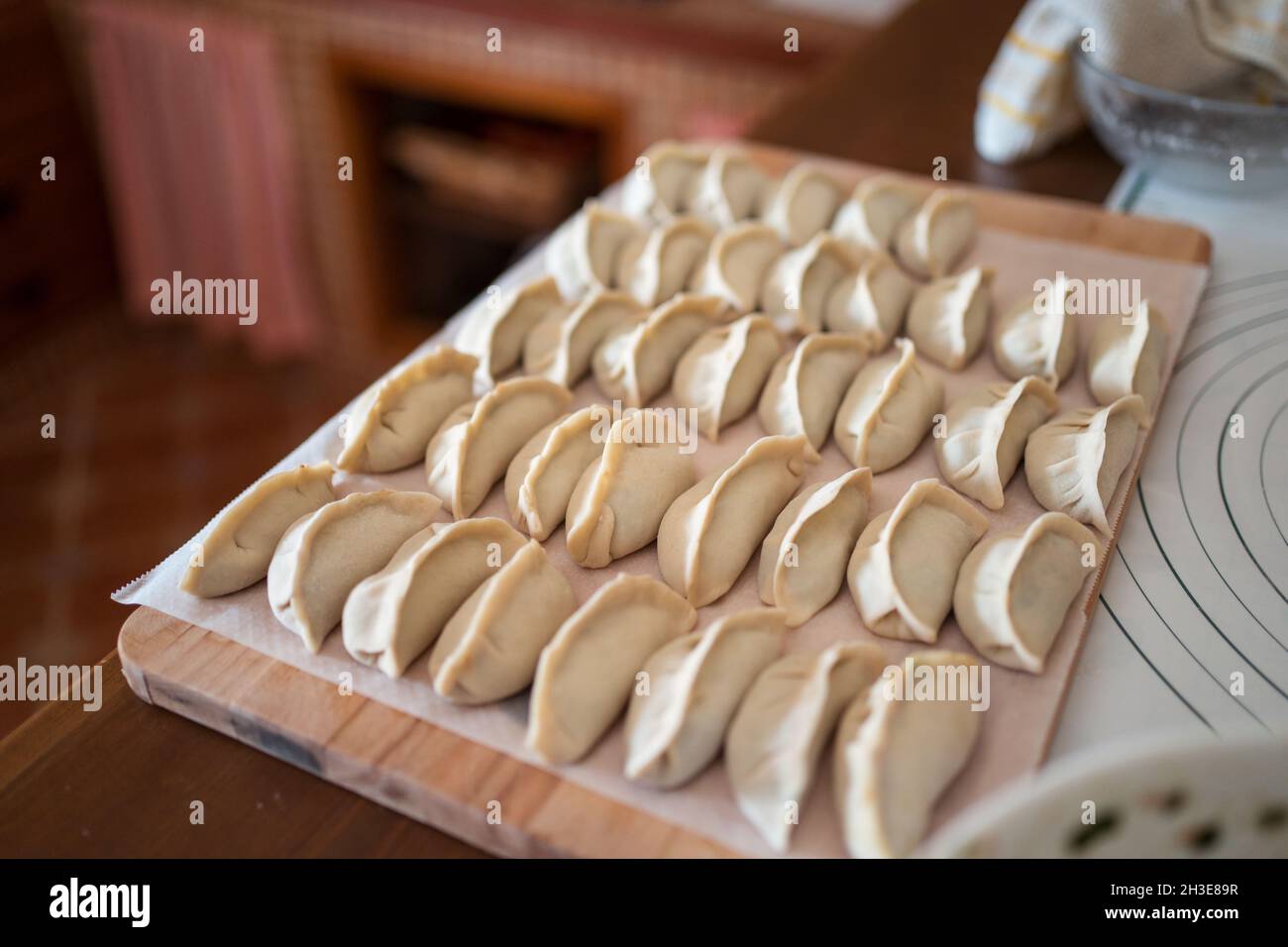 Da sopra di gnocchi tradizionali jiaozi crudi serviti su tagliere di legno in cucina Foto Stock