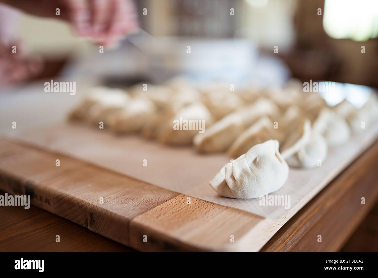Da sopra di gnocchi tradizionali jiaozi crudi serviti su tagliere di legno in cucina Foto Stock