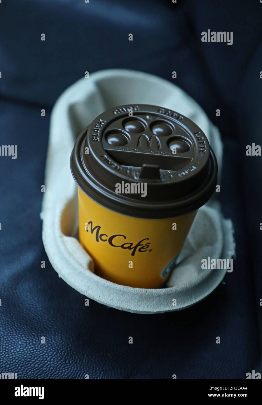 Un menu McDonald's in auto. Ecco una tazza di caffè sul sedile con il testo McCafé. McCafé è una catena di ristorazione in stile caffetteria, di proprietà del McDonald's. Foto Stock