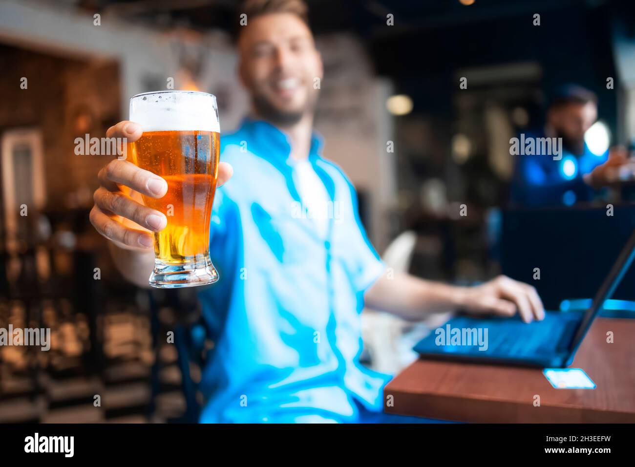 Un uomo che tiene rinfrescante bicchiere di birra Foto Stock