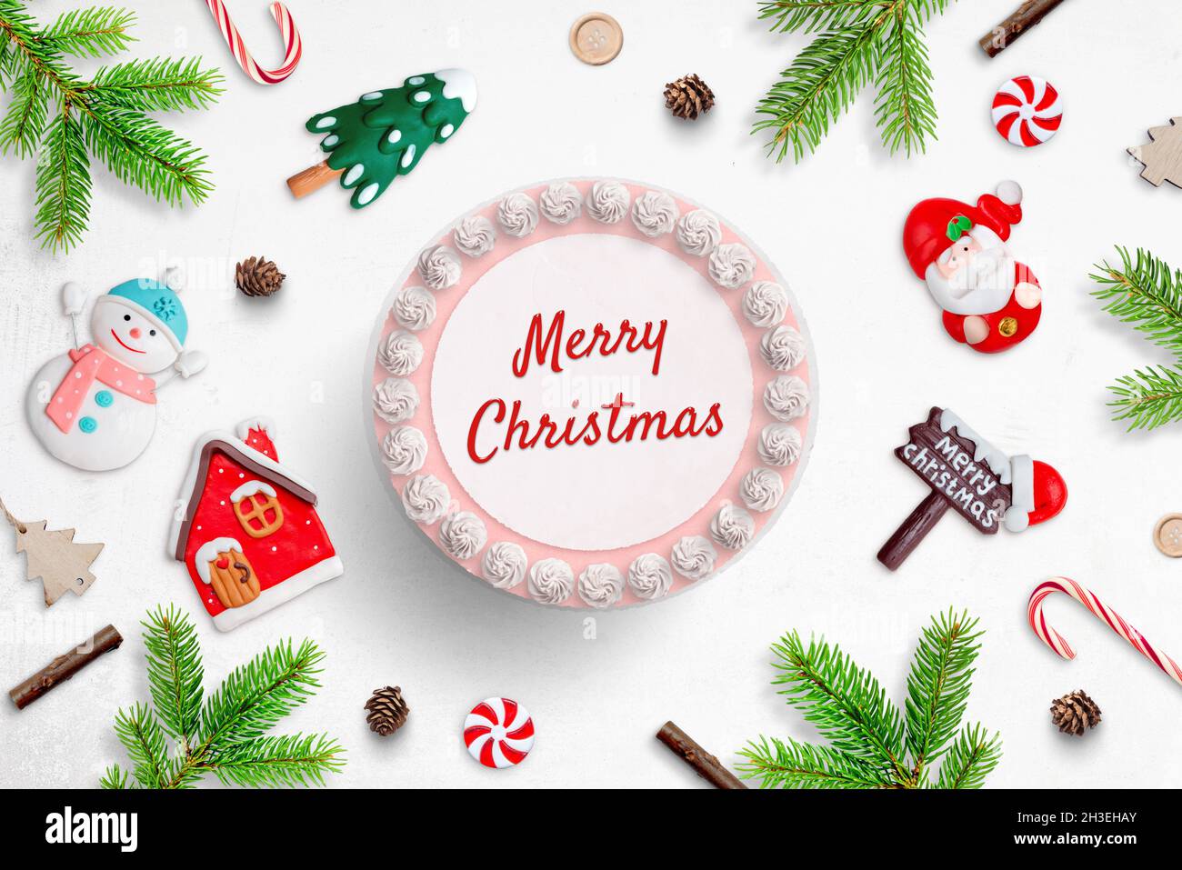 Fare un concetto di torta di Natale. Una torta con il testo del saluto di buon Natale, circondato da figurine fondanti Foto Stock