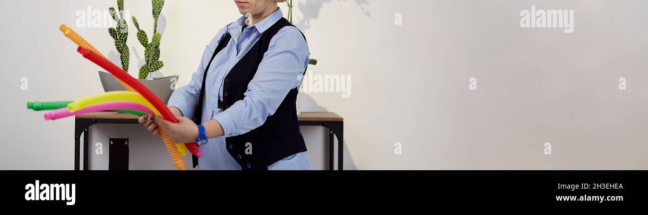 Lo psicologo infantile mostra una nuova tendenza nel giocattolo Pop tube. Colorato popolare giocattolo anti-stress sensoriale. Giocattolo alla moda per lo sviluppo di belle abilità motorie. Striscione extra largo. Spazio di copia. Foto Stock