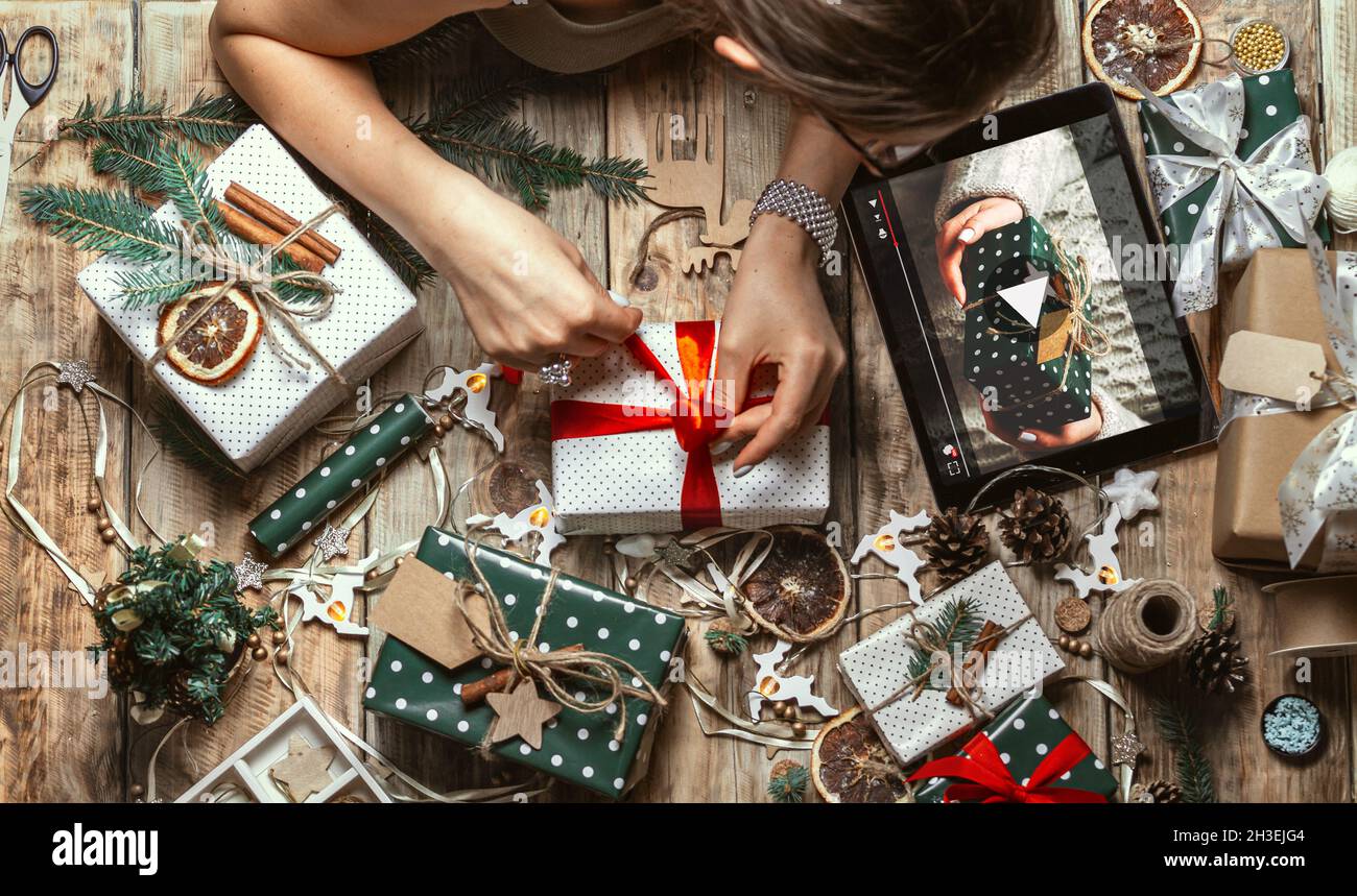 Donna mani avvolgere regalo di natale con tablet sul tavolo con chr Foto Stock