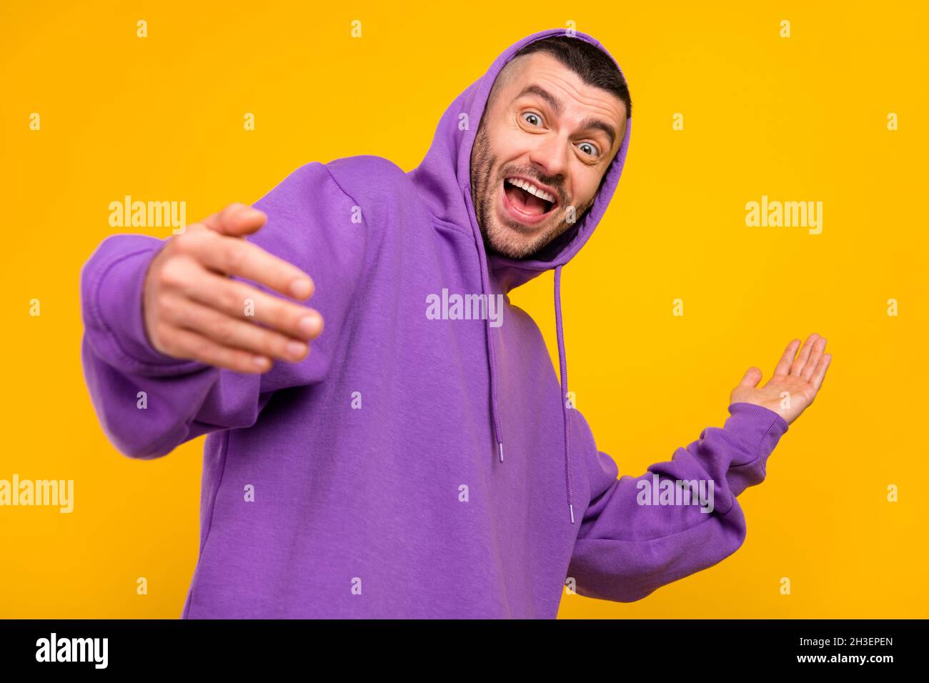 Foto di ragazzo funky brunet giovane indossare cappuccio viola isolato su sfondo giallo Foto Stock