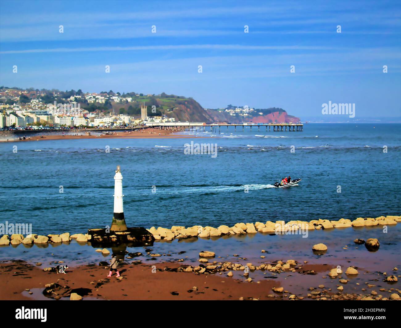 Teignmouth con il suo molo, la spiaggia e il lungomare. Alta la torre della chiesa di San Michele in Inghilterra. La scogliera di arenaria rossa conduce intorno al Foto Stock