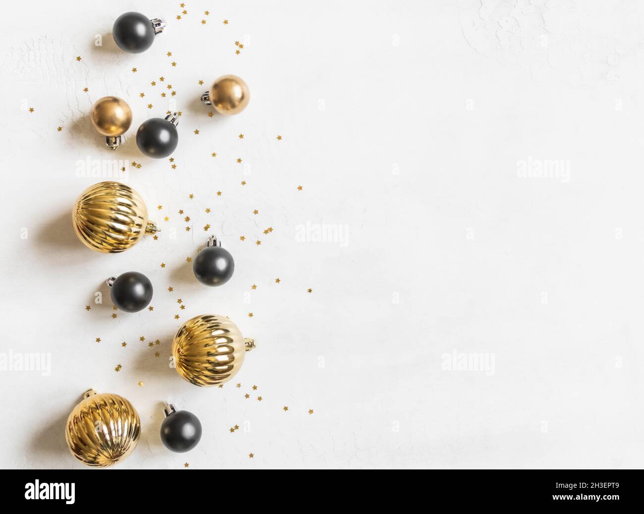 Biglietto d'auguri - buon anno e buon Natale, stelle d'oro brillano e palline di natale nero e oro su sfondo bianco testurizzato. Foto Stock
