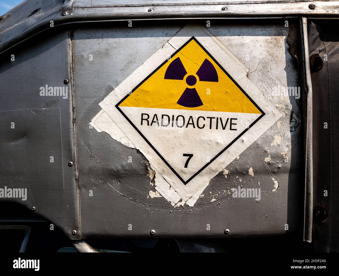Etichetta per il trasporto di radiazioni adesivo di classe 7 applicata sul vecchio adesivo sul contenitore in alluminio del carrello di trasporto Foto Stock