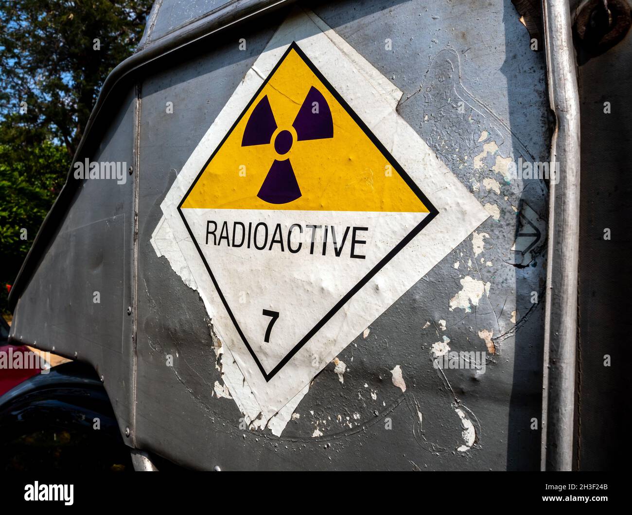 Etichetta per il trasporto di radiazioni adesivo di classe 7 applicata sul vecchio adesivo sul contenitore in alluminio del carrello di trasporto Foto Stock