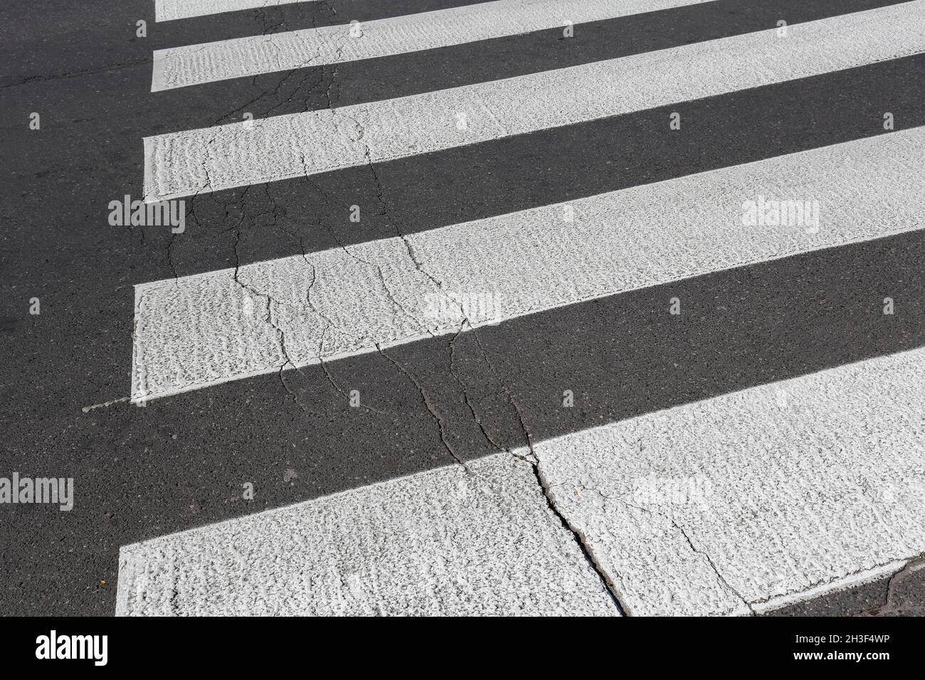Strisce bianche su asfalto nero è un passaggio pedonale. Foto Stock