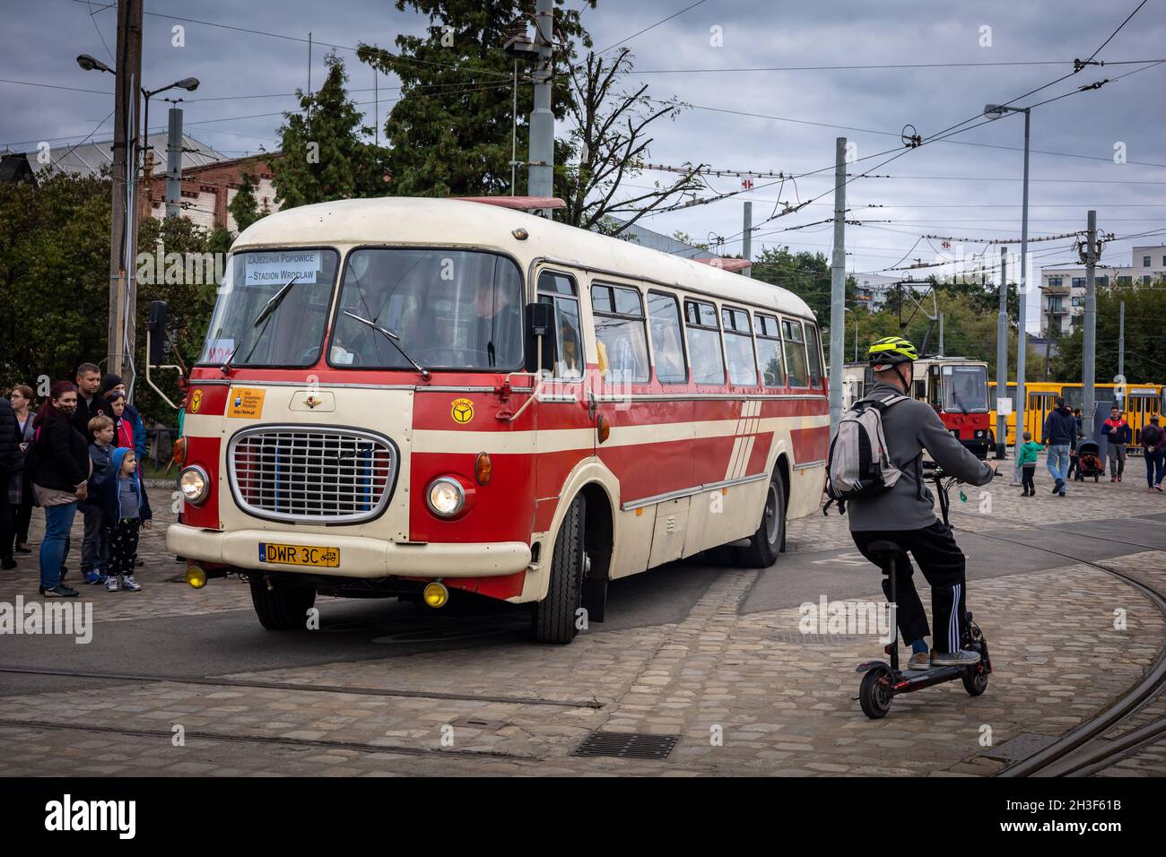 Wroclaw, Polonia - 19 settembre 2021: Una coda di passeggeri che entrano in vintage rosso e crema Skoda autobus alla stazione degli autobus. Uomo sullo scooter in primo piano. Foto Stock