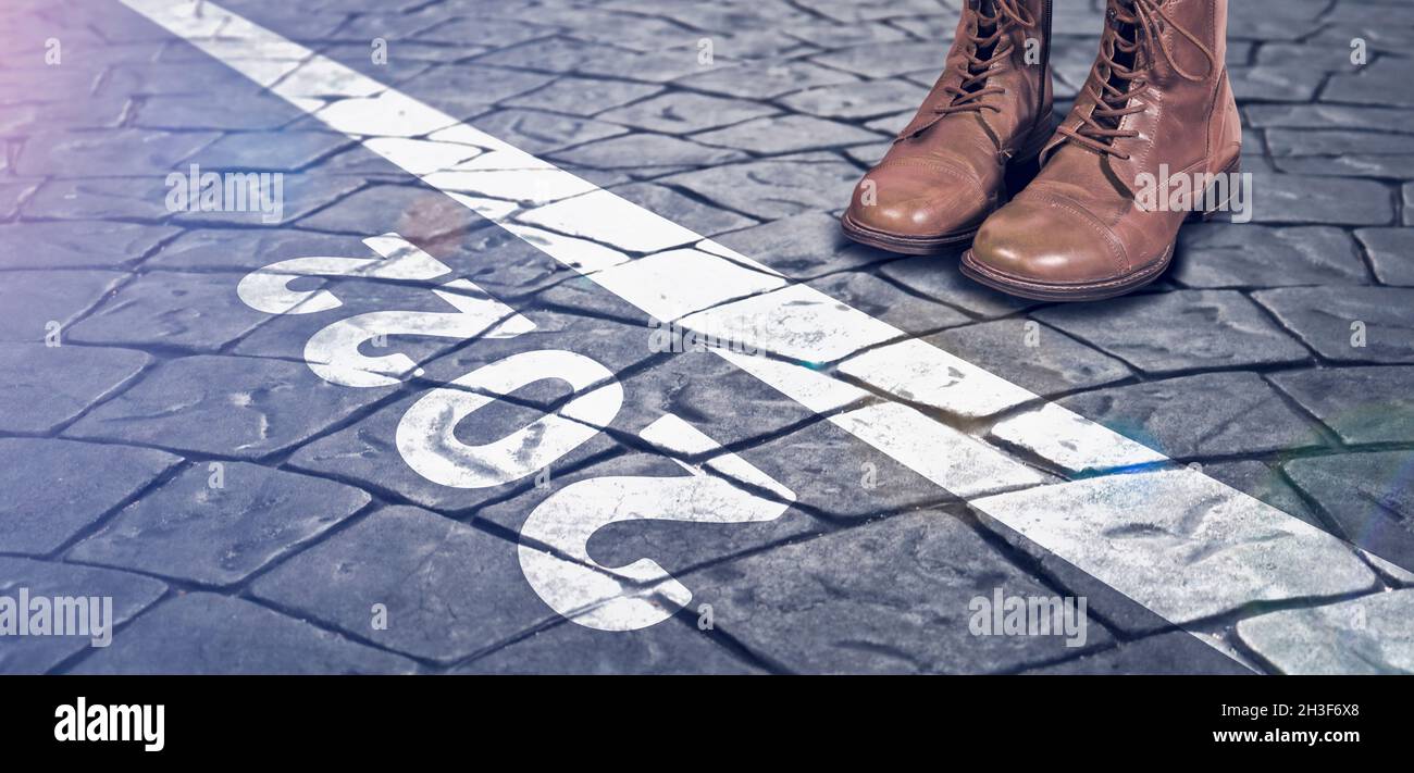 Piedi in stivali sulla strada acciottolata di fronte al testo 2022. Concetto di nuovo anno, nuove soluzioni e motivazione. Foto Stock