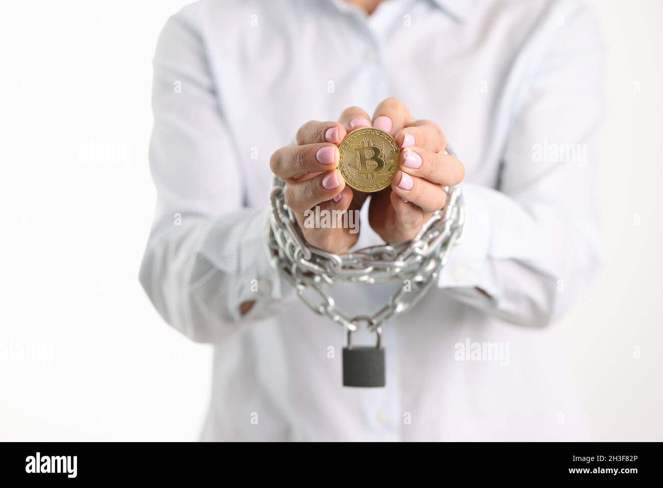 Donna con le mani legate della catena di metallo che tiene il closeup della moneta di bitcoin Foto Stock