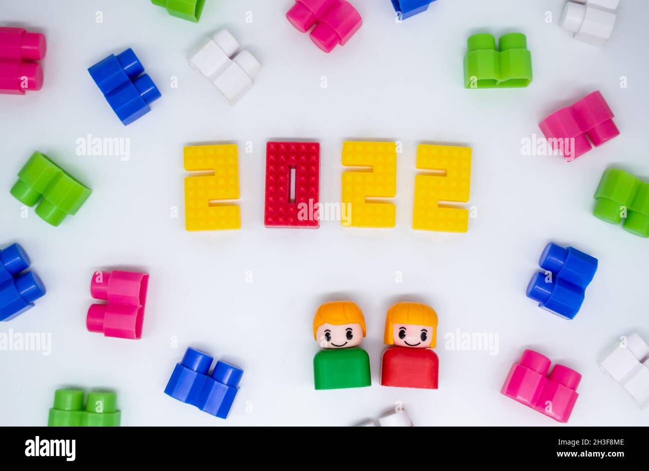 Blocchi di costruzione colorati, giocattoli figure in plastica: 2022 numeri, ragazzo e ragazza su sfondo bianco. Foto Stock