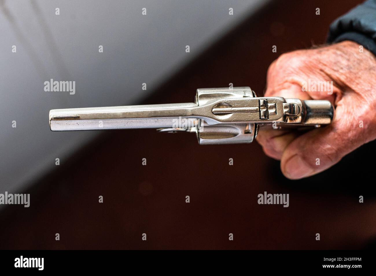 Una vecchia mano che tiene un revolver antico in una posizione di scatto Foto Stock