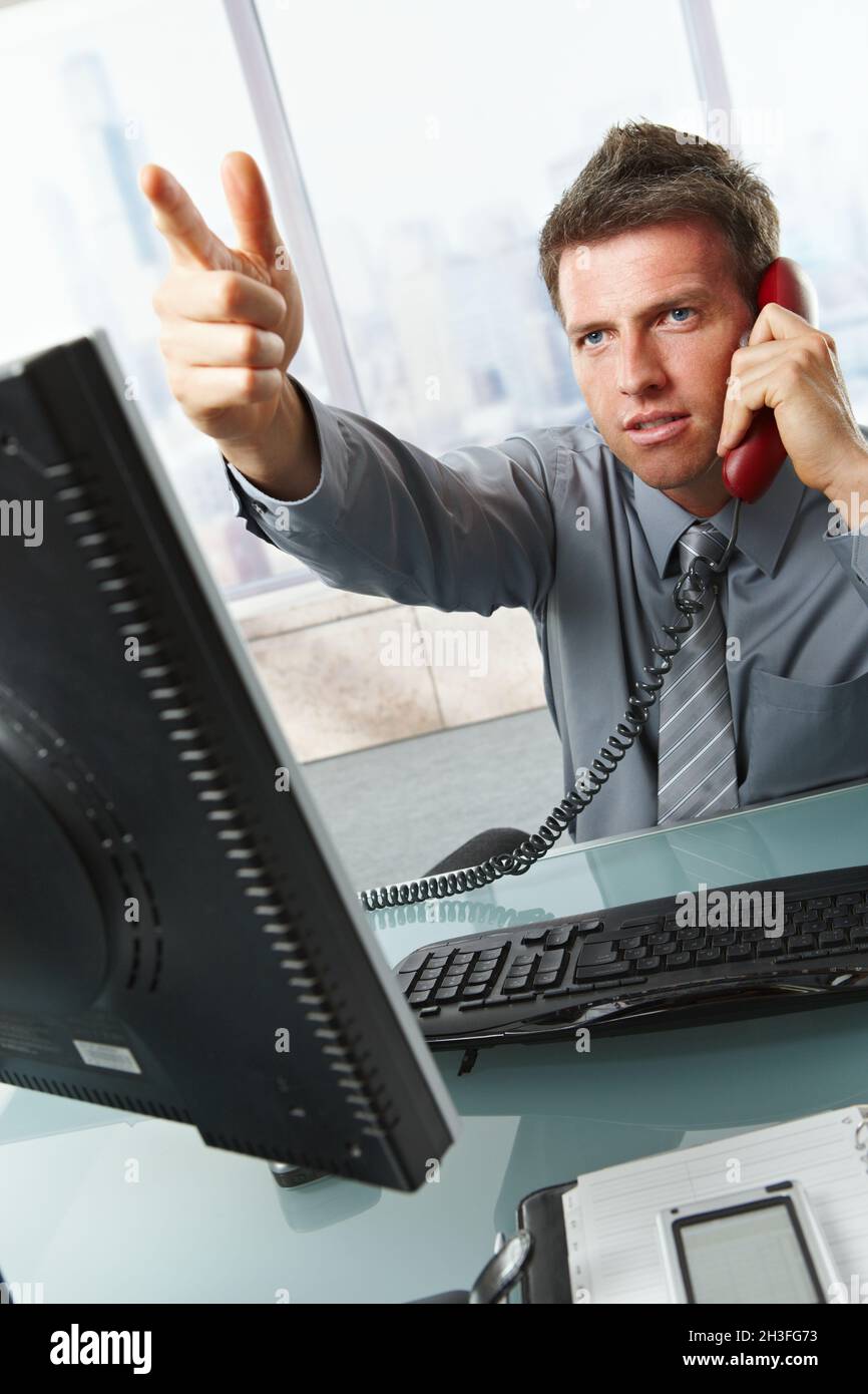 Uomo d'affari che chiama e gesturing in ufficio Foto Stock