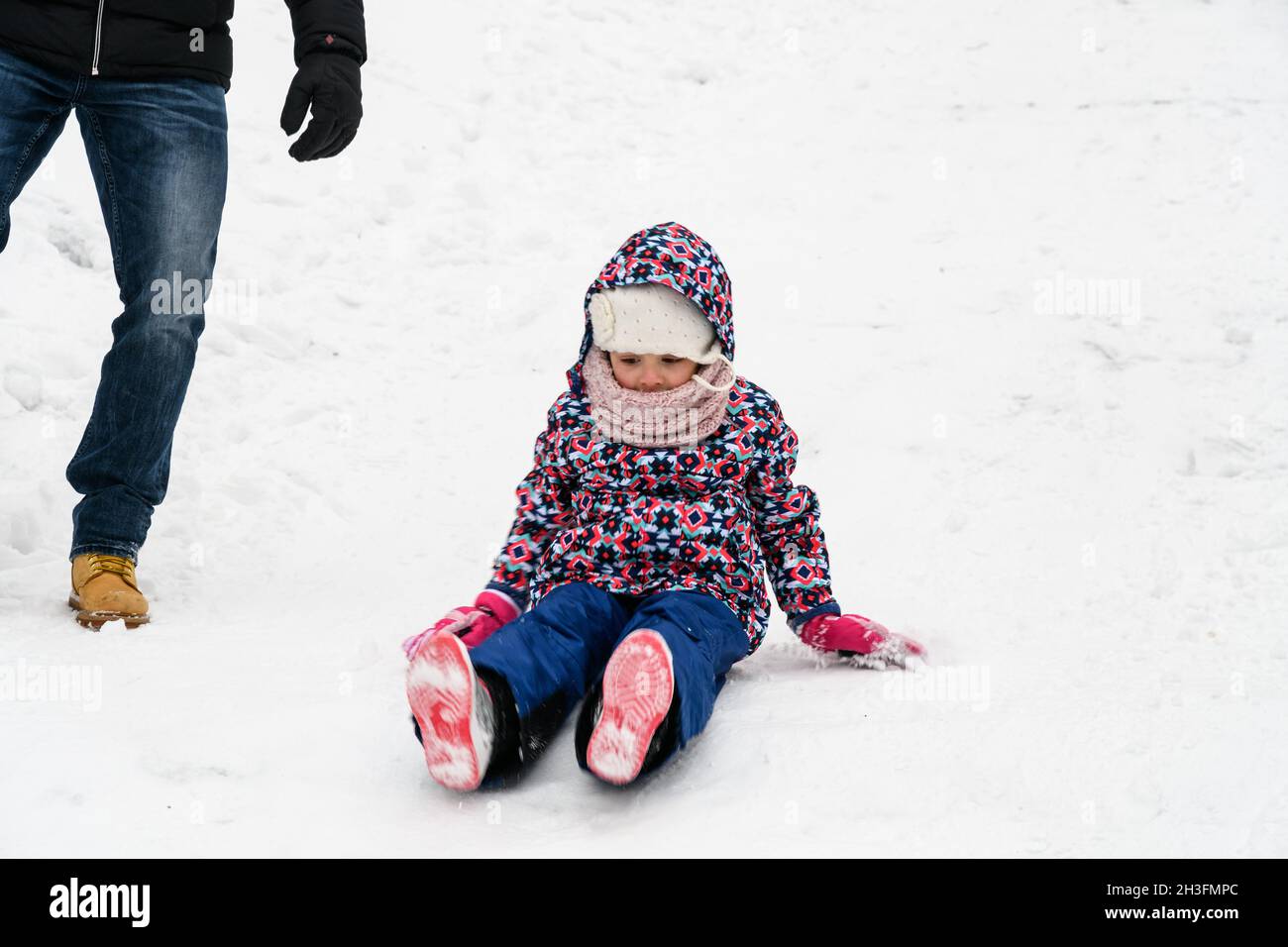 sorprendente scivolamento e caduta nella neve quando si cammina in una giornata invernale Foto Stock