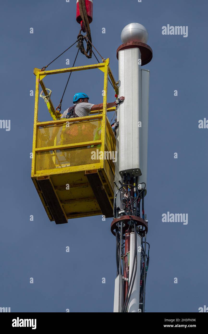 Due tecnici lavorano per completare gli aggiornamenti della torre del cellulare durante le trattative del Congresso sulla spesa per le infrastrutture. Foto Stock