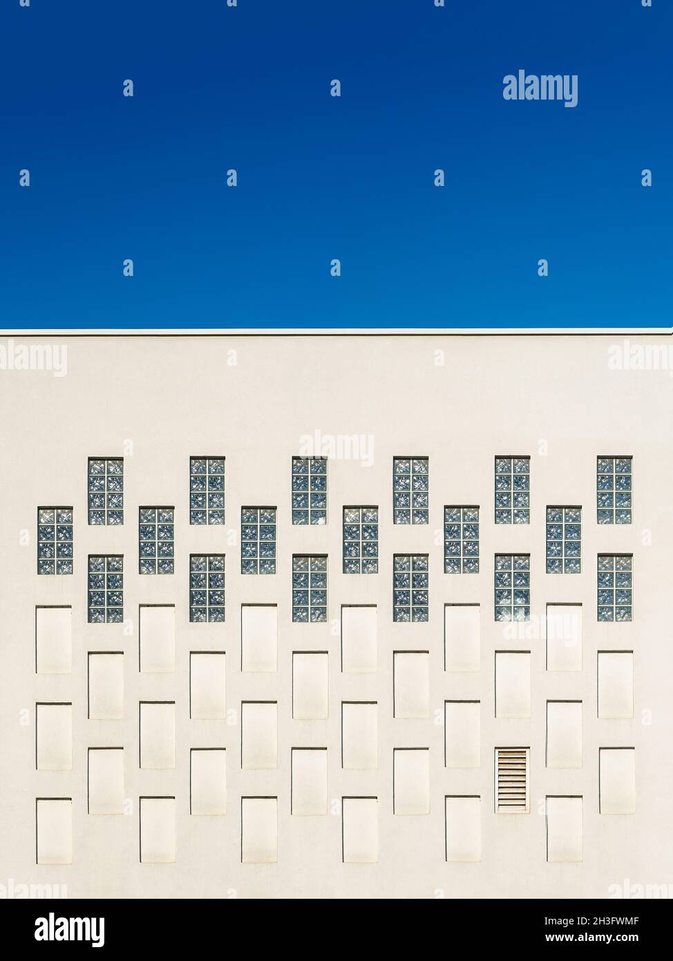 Finestre rettangolari e nicchie nella parete esterna dell'edificio contro il cielo blu. Elementi architettonici che ripetono il modello della moderna struttura. Foto Stock