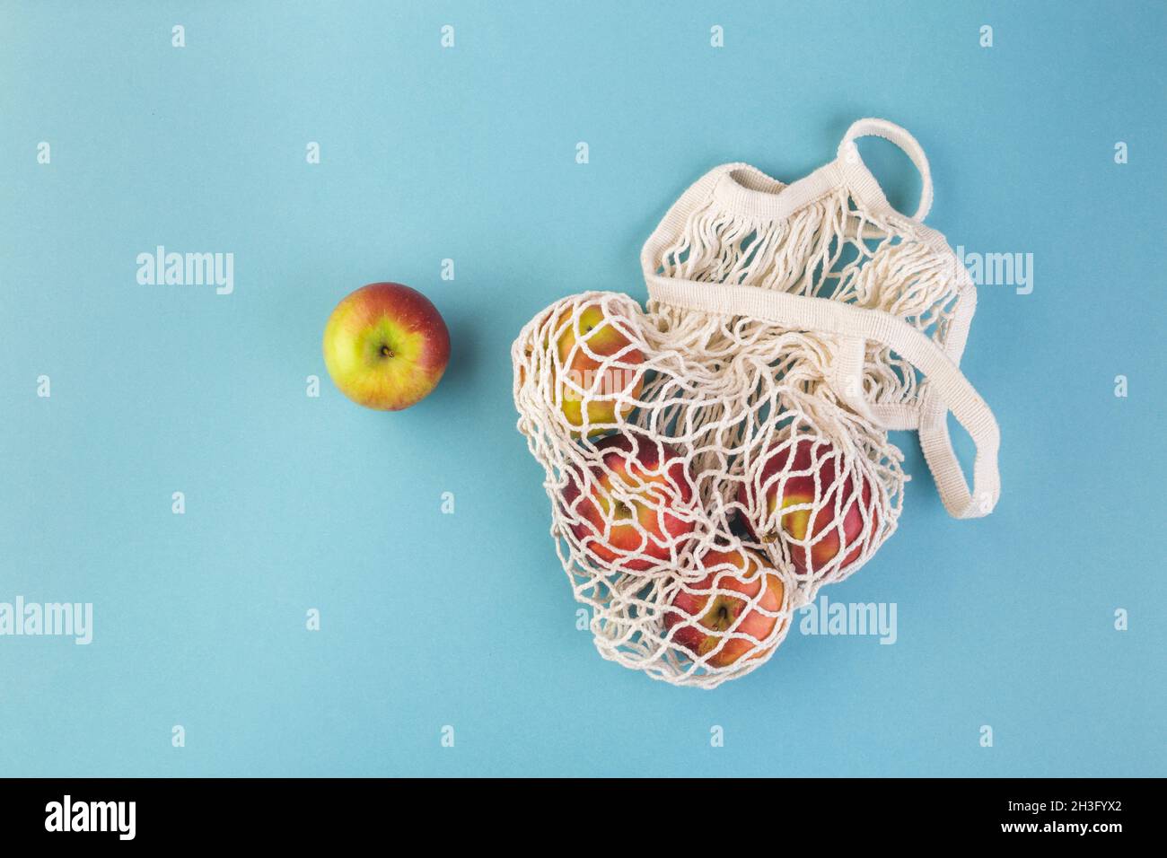 Borsa di mela rossa e string su un tavolo blu. Stagione estiva o autunnale. Concetto di shopping ecologico Foto Stock