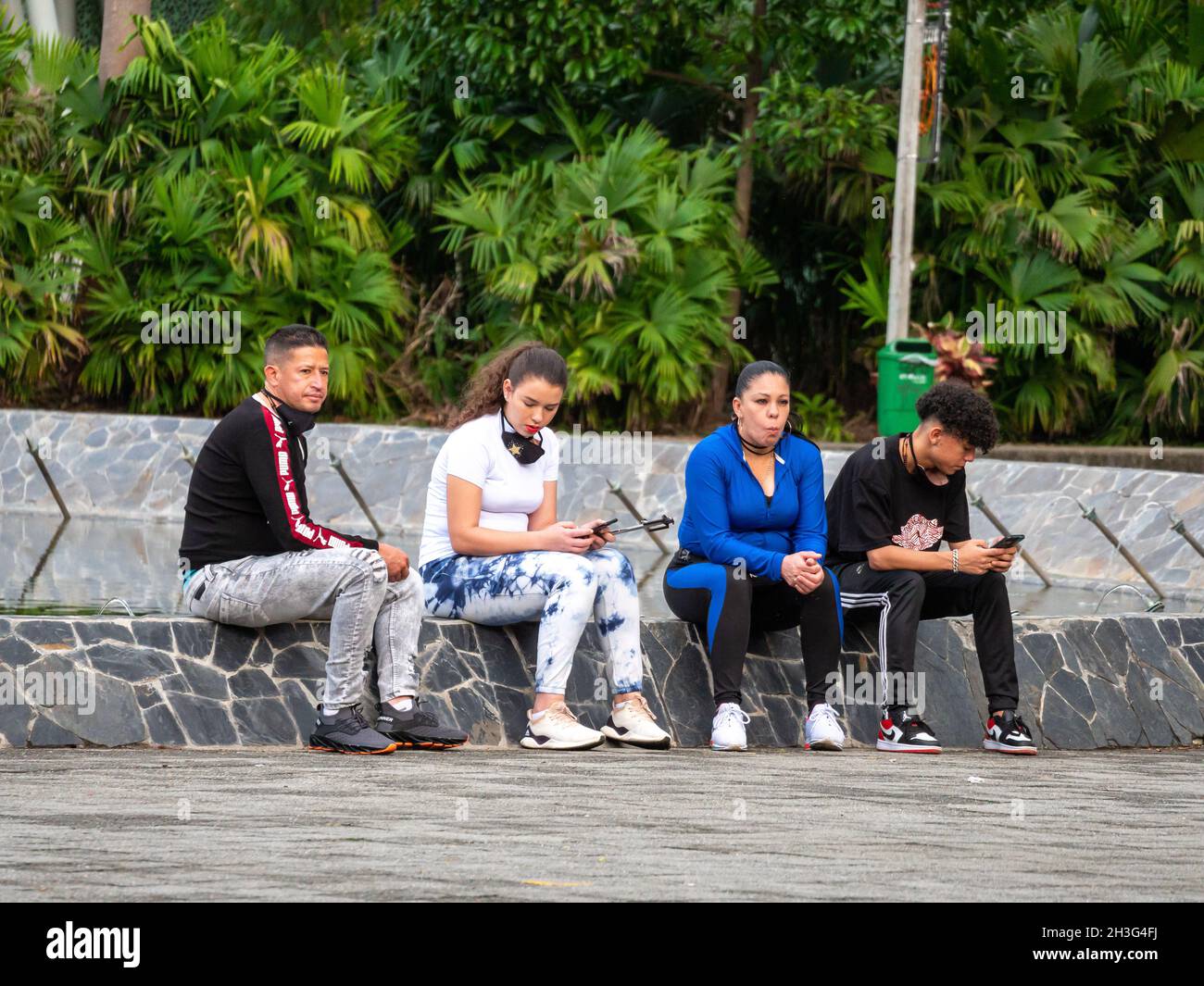 Medellin, Antioquia, Colombia - Dicembre 22 2020: Amici seduti in una fontana in un parco pubblico Foto Stock