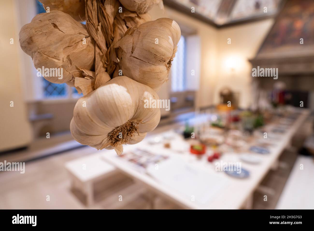 La treccia di aglio appesa con un tavolo posto sullo sfondo Foto Stock