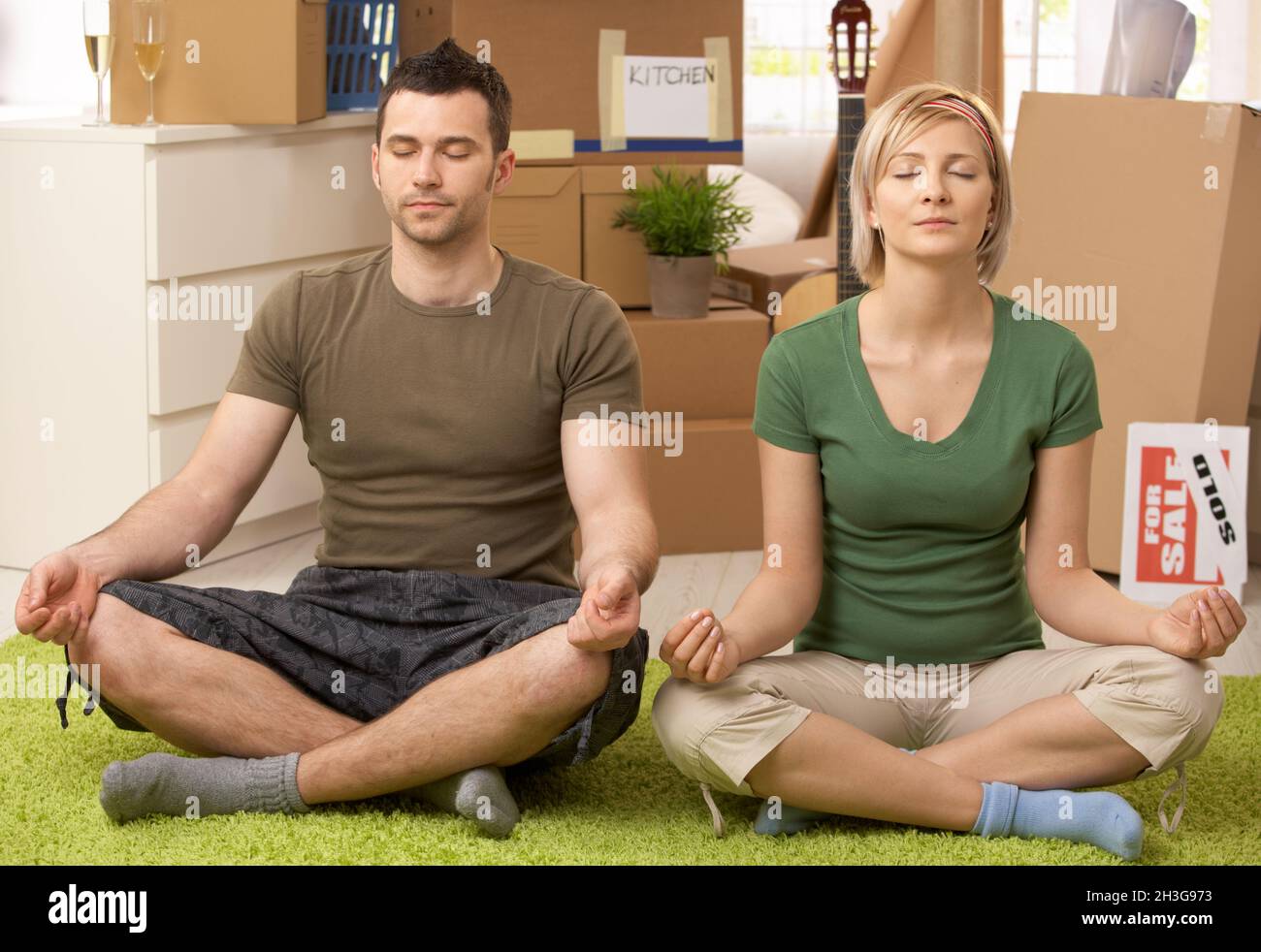 Giovane coppia che fa yoga a casa nuova Foto Stock