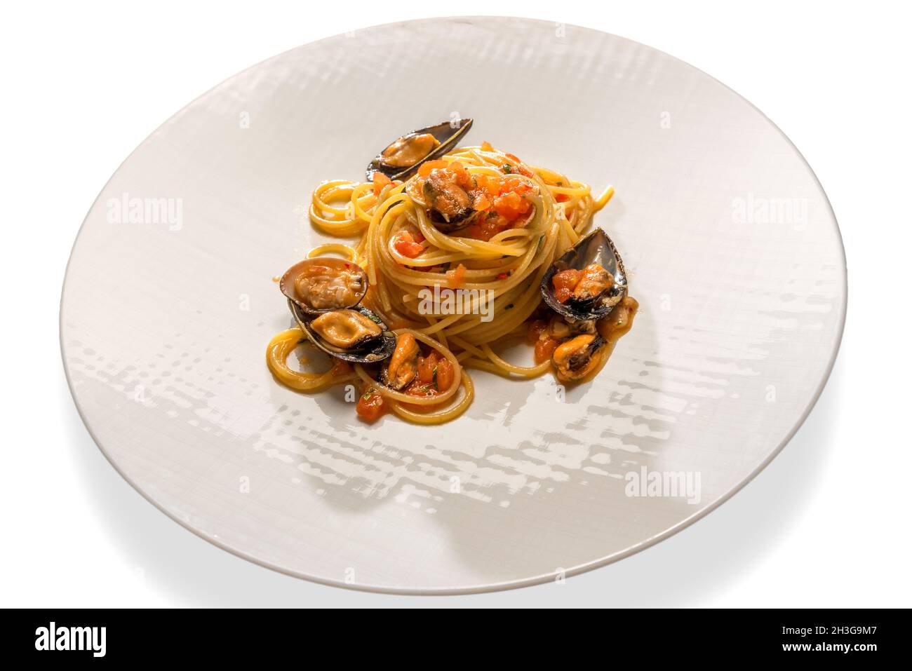 Spaghetti con frutti di mare, pasta con cozze, vongole e salsa di pomodoro fresco alla ciliegia in piatto bianco isolato su bianco Foto Stock