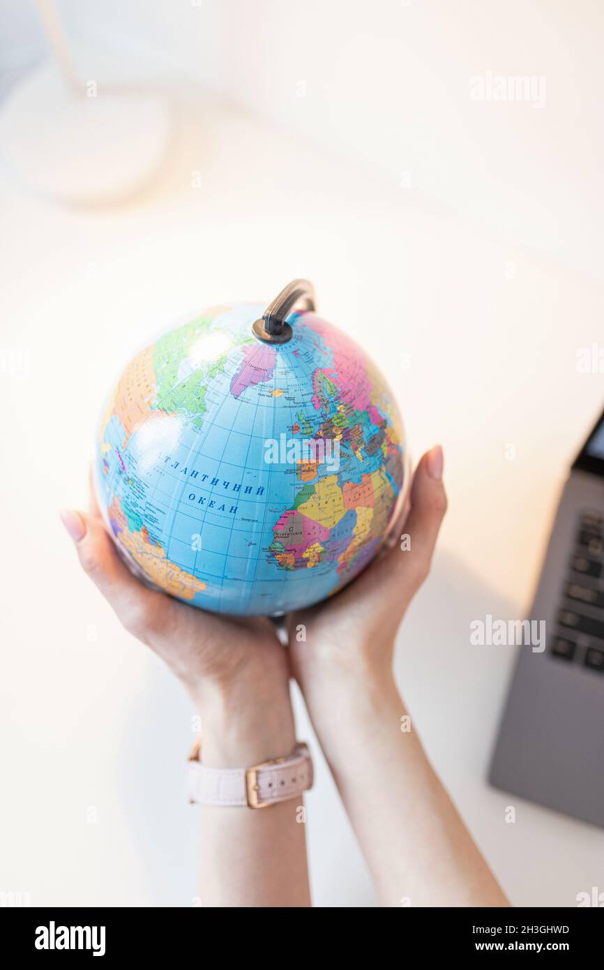 La donna tiene il globo nelle sue mani sopra il tavolo. Concetto di viaggio Foto Stock