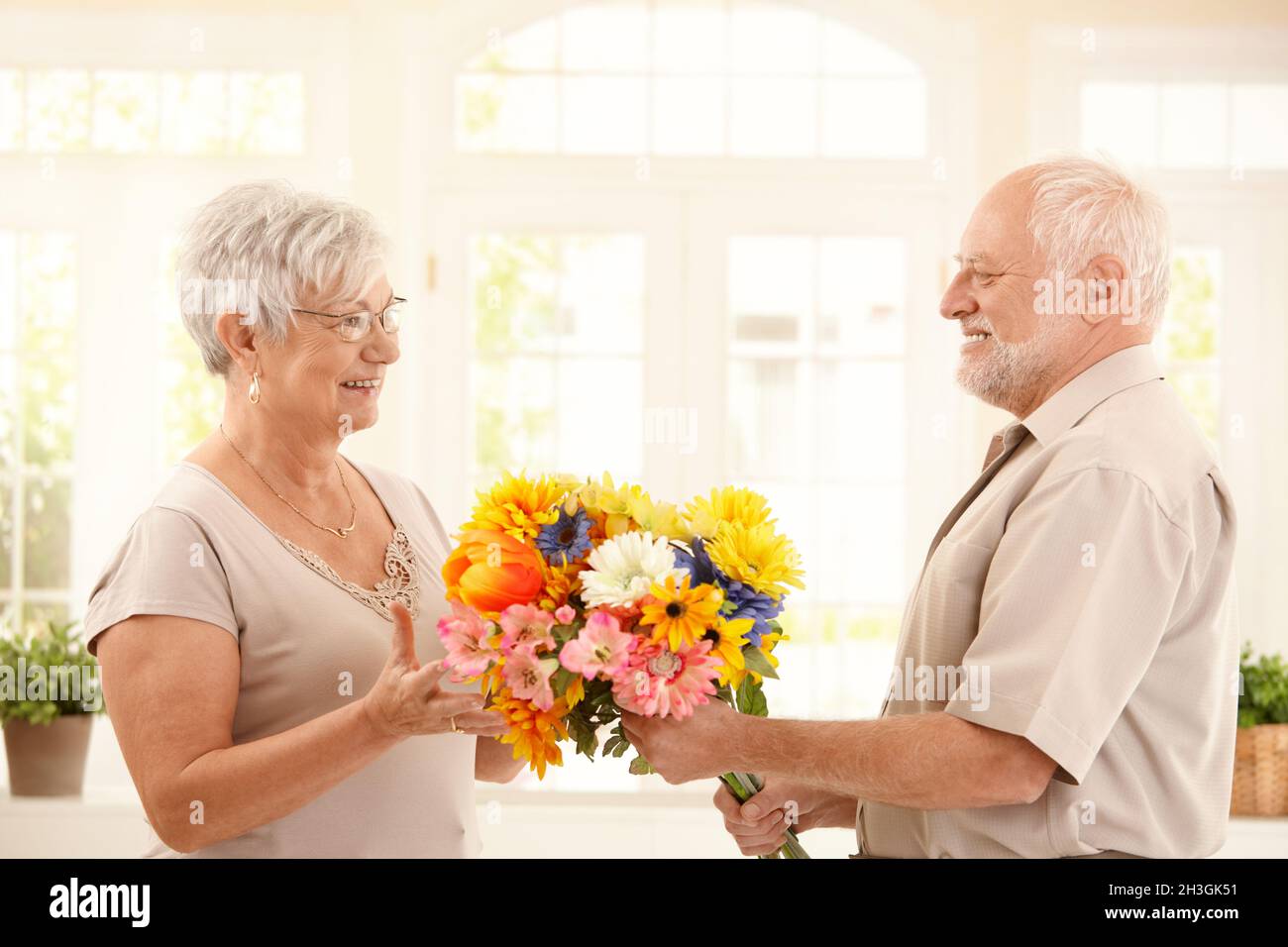 Uomo anziano che porta fiori in moglie Foto Stock