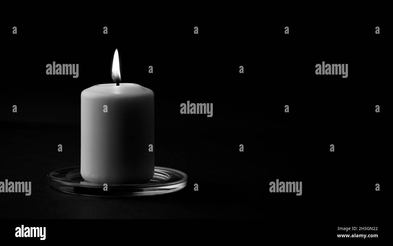 candele con fiamma e libro di lettura sulla scrivania, sfondo nero.  (focalizzazione sulla candela Foto stock - Alamy