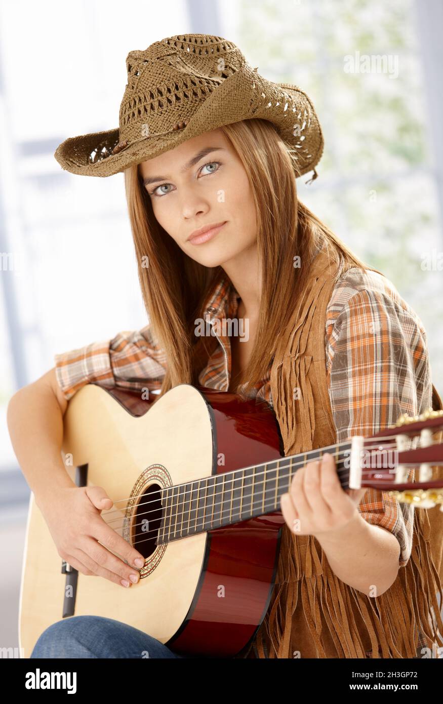 Attraente chitarrista che pratica in cappello occidentale Foto Stock