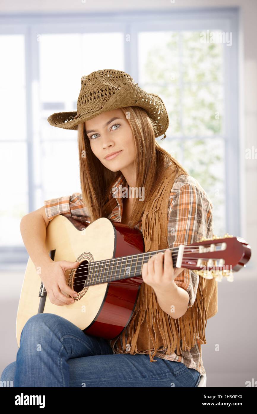 Bella ragazza che suona la chitarra in cappello occidentale Foto Stock