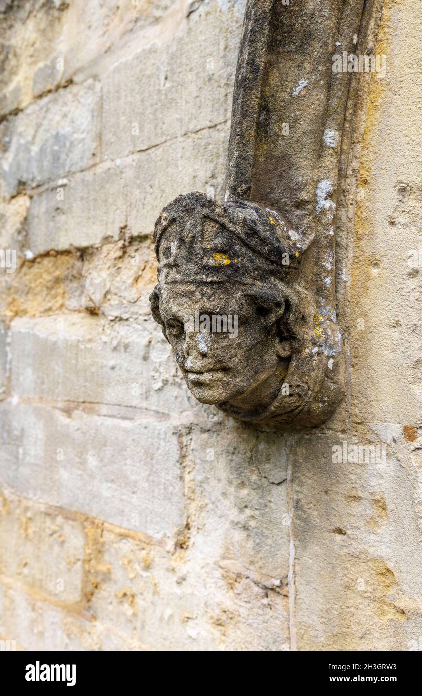 Testa di figura di pietra intagliata con intemperie, Chiesa di St Andrew, Castle Combe, un villaggio nella zona di bellezza naturale di Cotswolds, Wiltshire, Inghilterra sud-occidentale Foto Stock