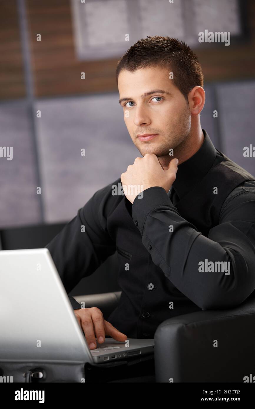 Uomo d'affari in nero che lavora su un notebook Foto Stock