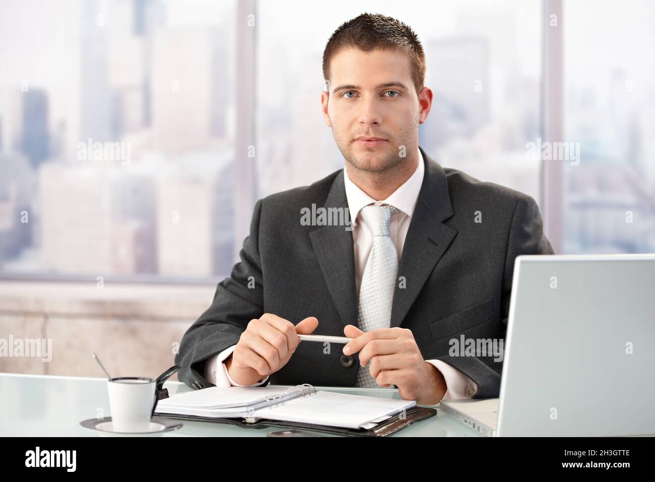 Elegante uomo d'affari seduto in un luminoso ufficio Foto Stock