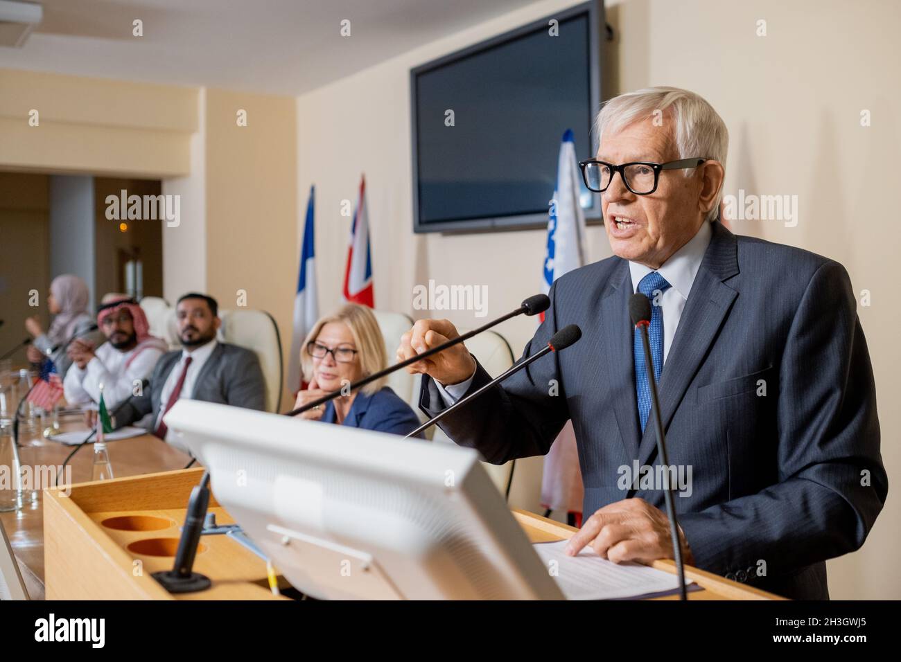 Uomo politico emozionale anziano dai capelli bianchi in occhiali e vestire  la mano gesturante, dando un discorso ispiratore alla conferenza stampa  Foto stock - Alamy
