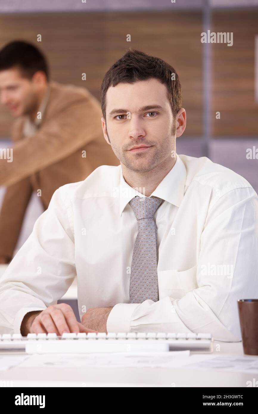Ritratto di un lavoratore di ufficio casual seduto alla scrivania Foto Stock