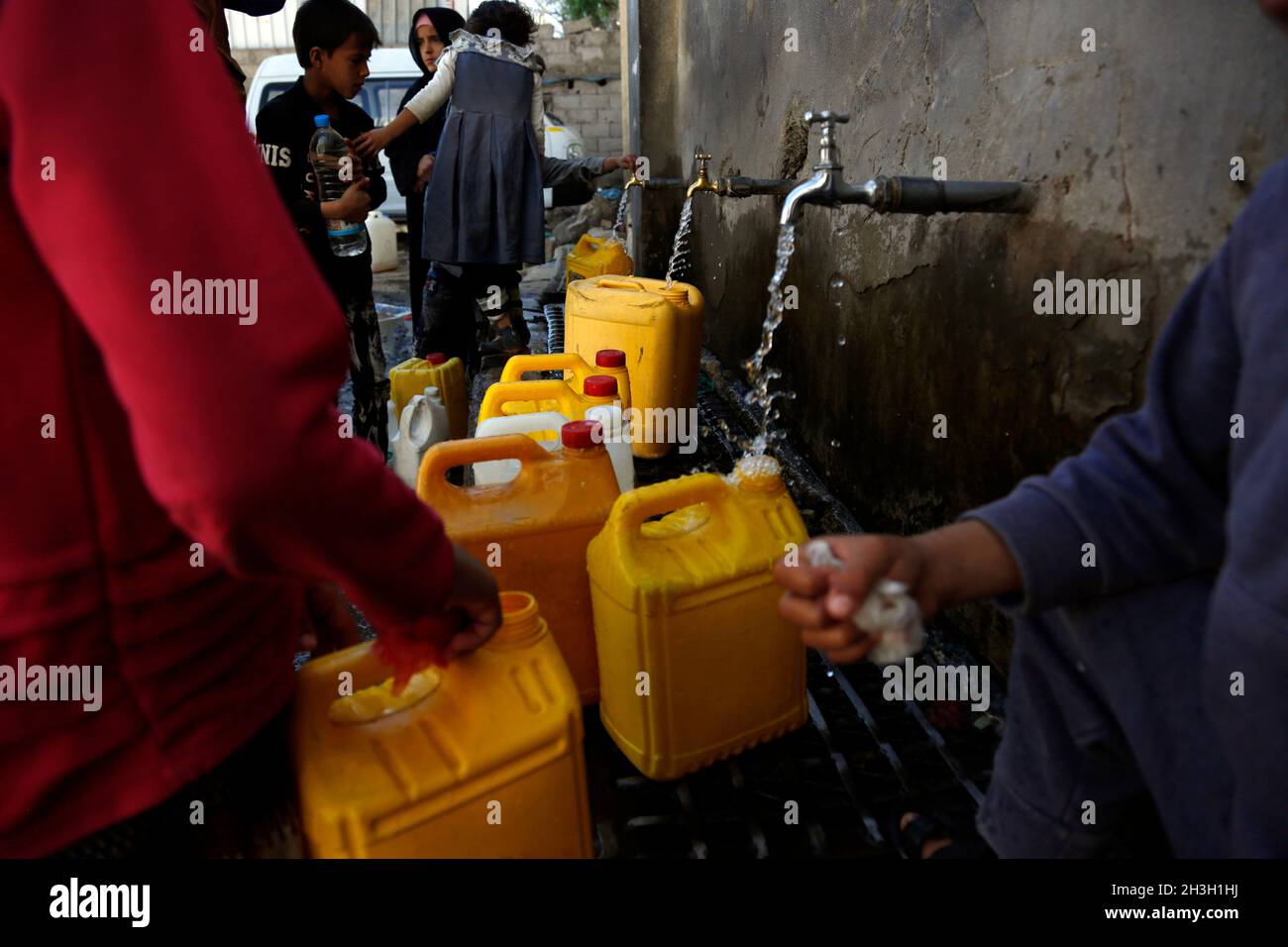 Sanaa, Yemen. 28 ottobre 2021. I bambini yemeniti riempiono i contenitori di plastica con l'acqua ad un luogo di rubinetto dell'acqua di carità a Sanaa, Yemen, il 28 ottobre 2021. Credit: Nyooooooooooooooooooooooooooooo Foto Stock