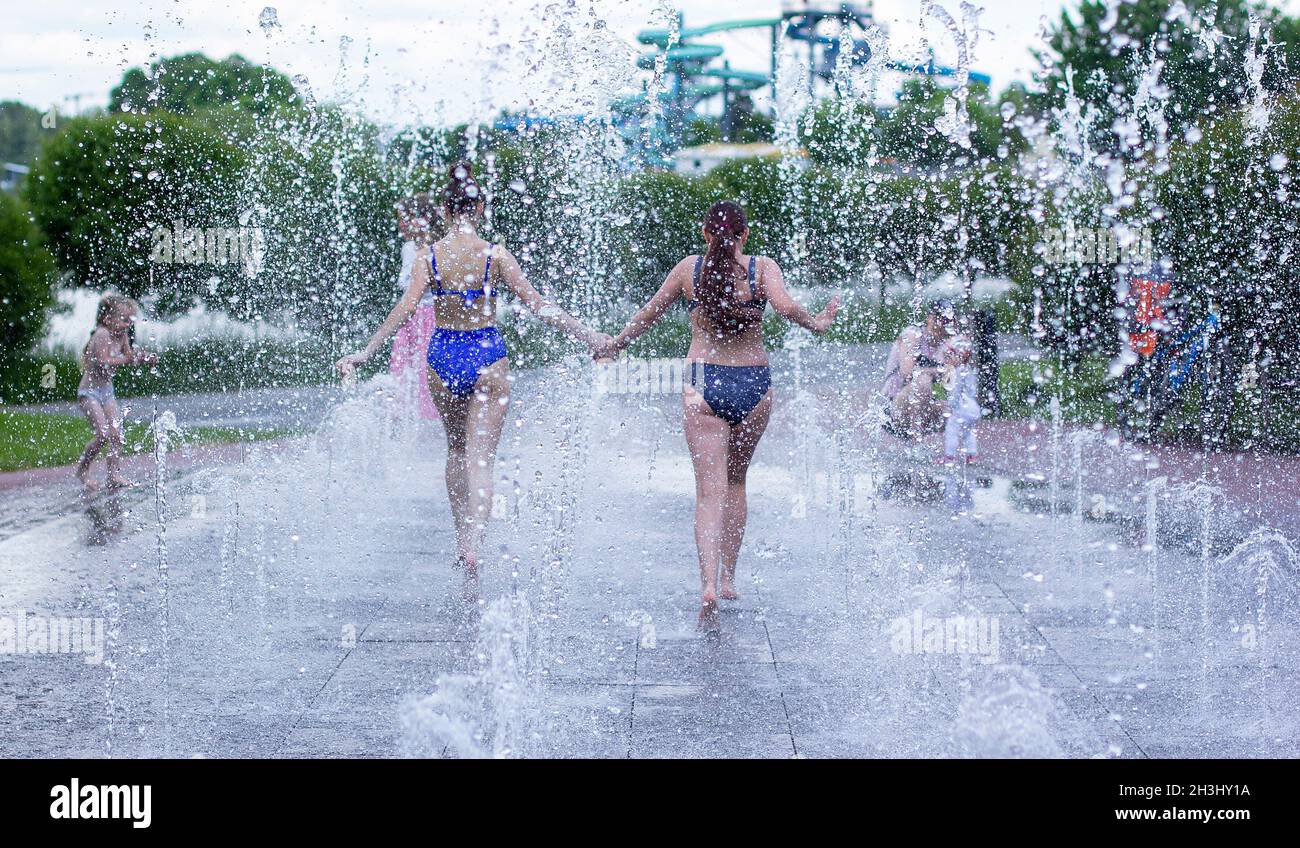 Minsk. Bielorussia. 12 giugno 2021. Fontana vicino al Marriott Hotel. Le ragazze adolescenti felici spruzzano nell'acqua della fontana della città e godono i getti freddi o Foto Stock