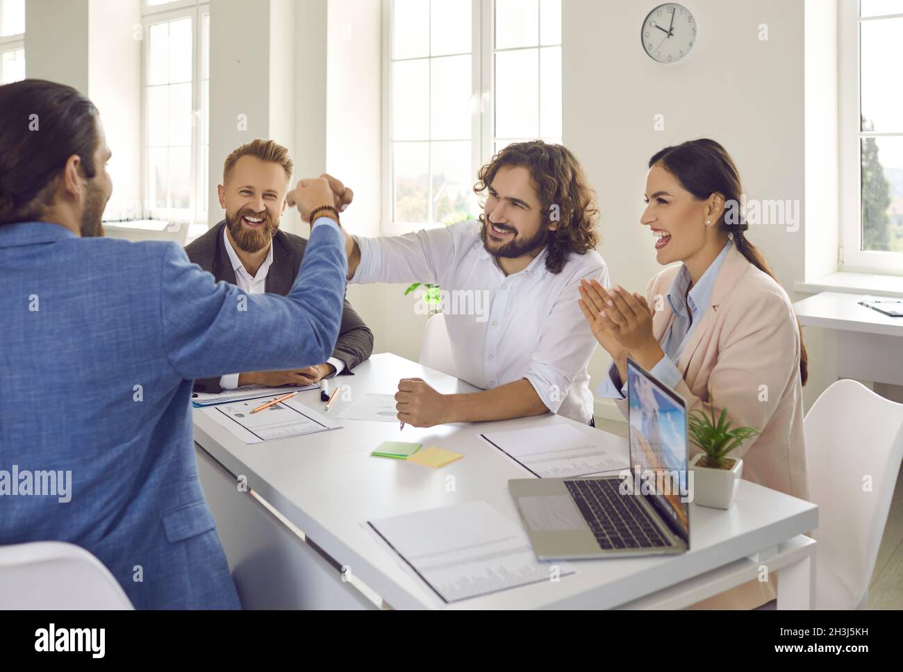 Felice gente di affari che siede ad una scrivania di ufficio e sbatte dopo aver fatto un affare Foto Stock