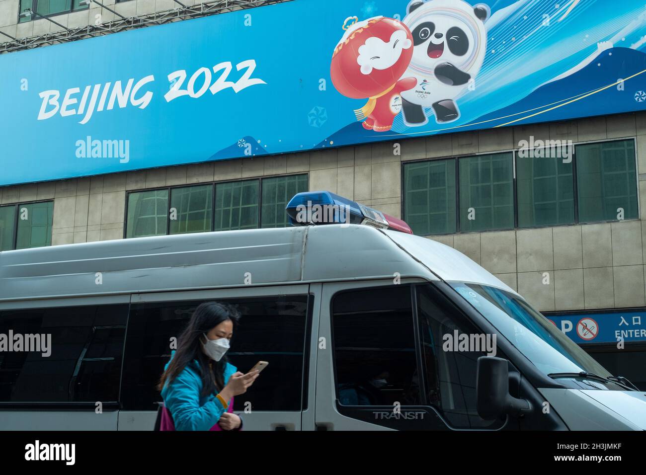 Una signora cammina davanti a un negozio di merci autorizzato per le Olimpiadi invernali del 2022 a Pechino, Cina. 29 ottobre 2021 Foto Stock