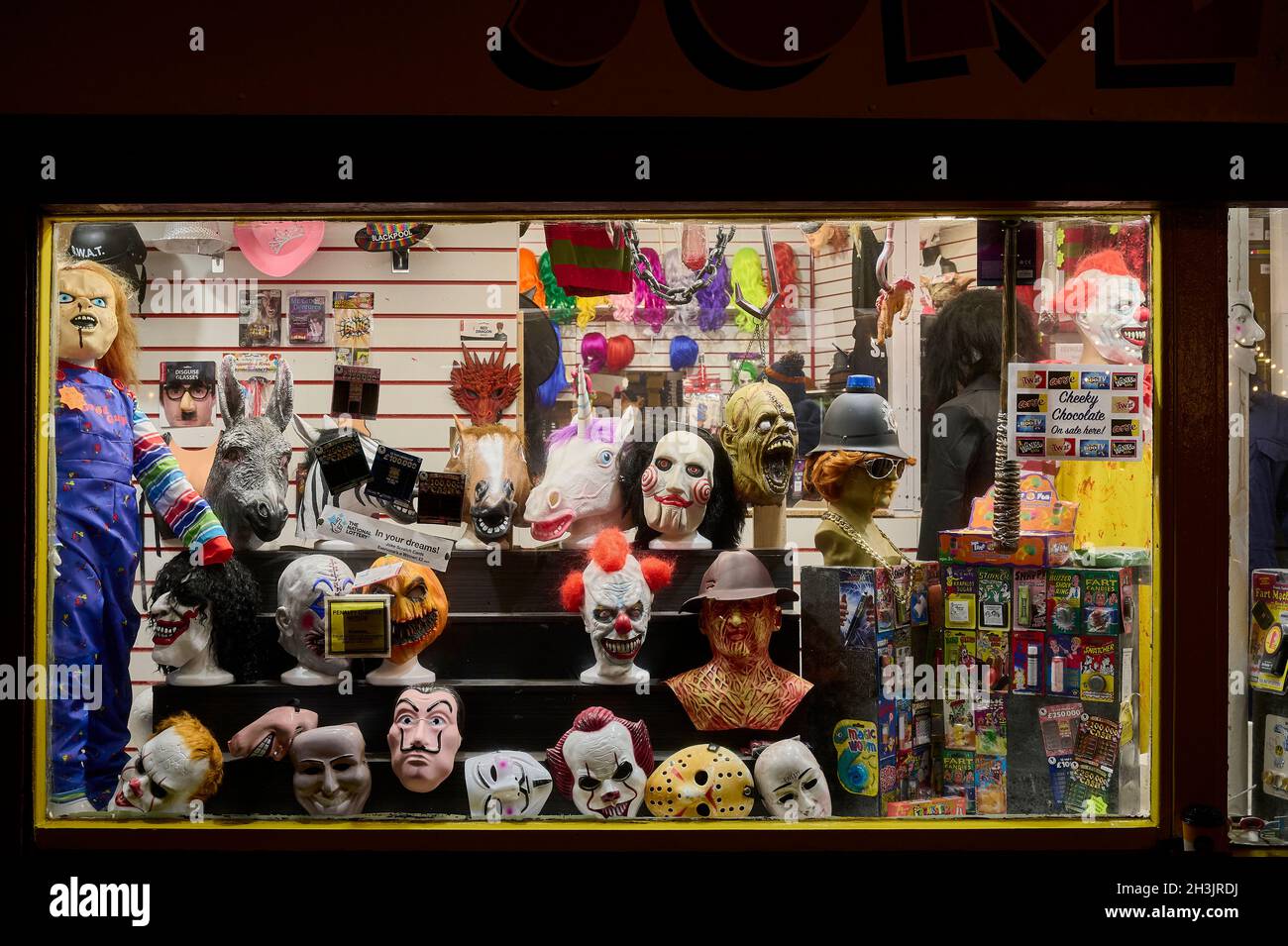 Elegante vetrata di negozi di abbigliamento di notte con maschere horror halloween Foto Stock