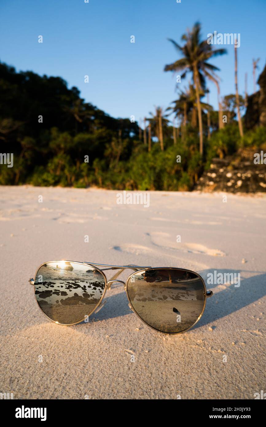 Occhiali da sole sulla spiaggia sabbiosa su sfondo tropicale dell'isola Foto Stock