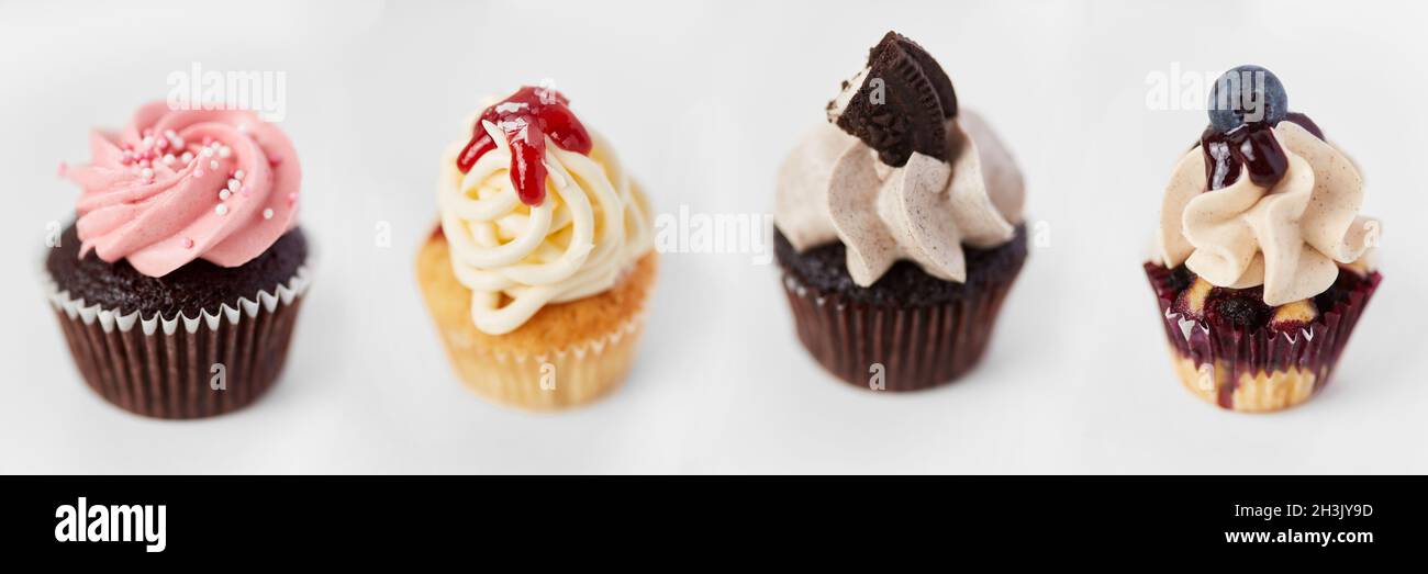 Molti cupcake decorati e colorati con condimenti si trovano in fila l'uno accanto all'altro Foto Stock