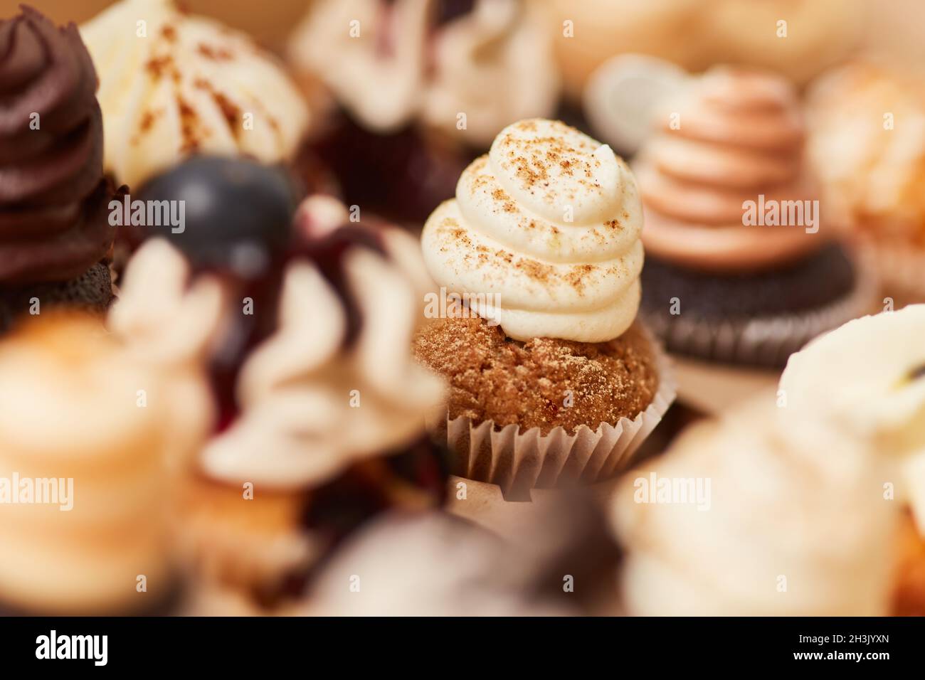 Un sacco di piccoli cupcake decorati con condimenti in una panetteria Foto Stock