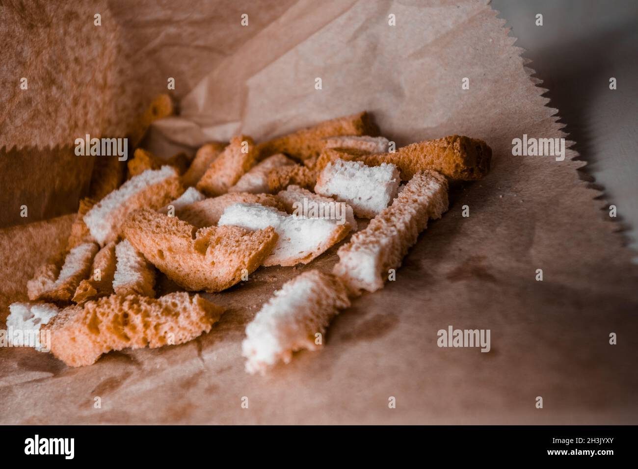 Un mucchio di lunghi crostini di pane bianco fritto giacciono in carta artigianale. Foto Stock