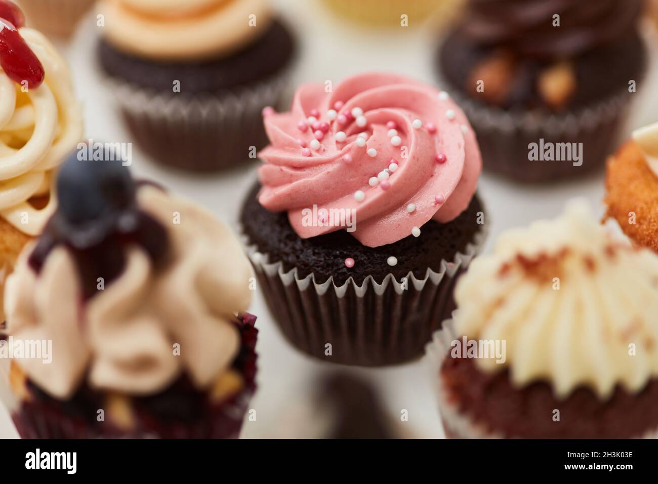 Cupcake al cioccolato con crema di lamponi e perle di zucchero come decorazione Foto Stock