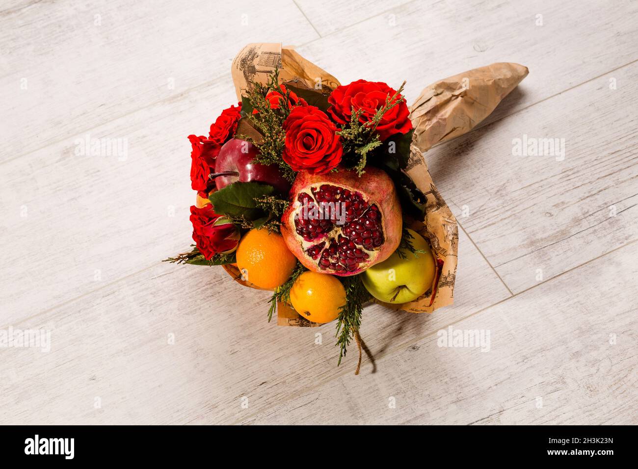 Graziosamente avvolto composizione di rose rosse e frutti. Foto Stock