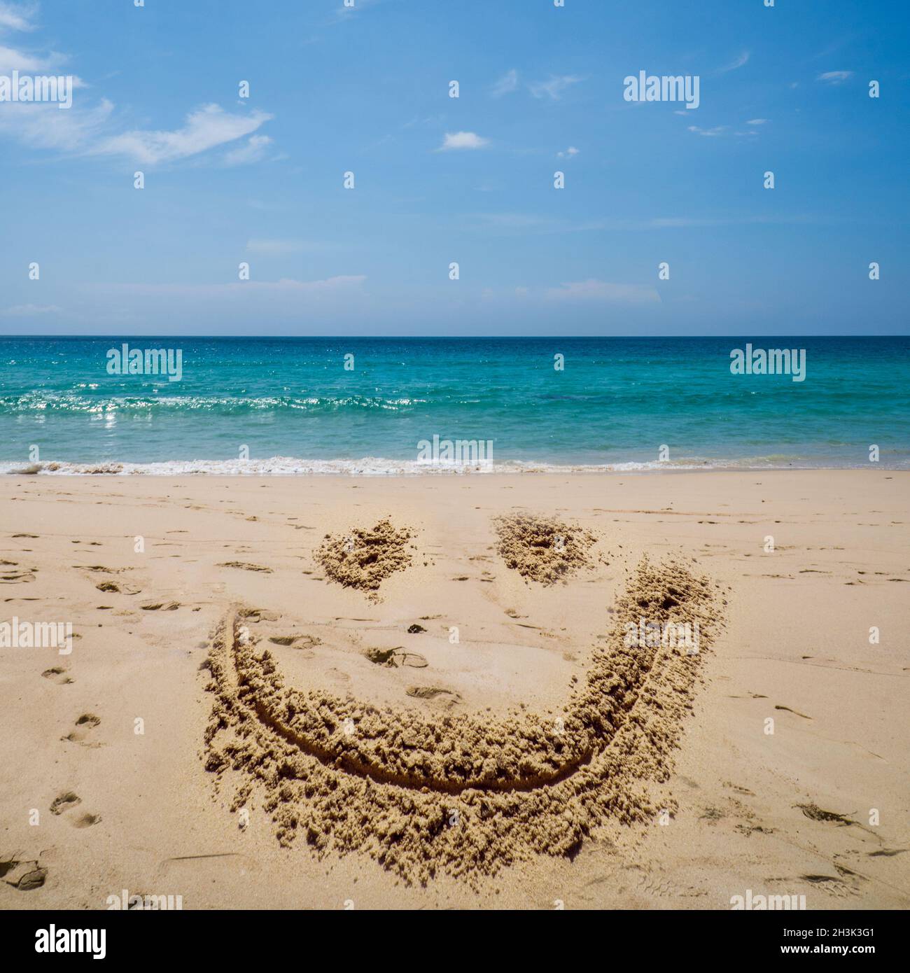 Smilinig faccia disegnare sulla spiaggia sopra il mare Foto Stock