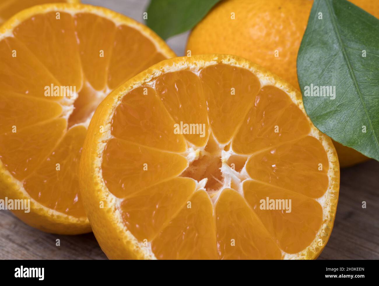 Fresche e mature tangerini con foglie su un sfondo di legno. Vista ravvicinata. Foto Stock